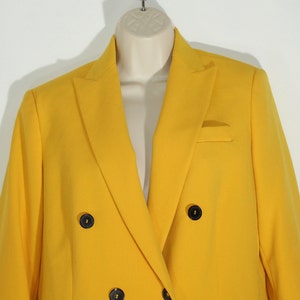 Puede incluir: Una chaqueta amarilla brillante de doble botonadura con botones negros.