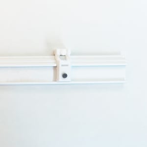 May include: White plastic bracket with a screw for mounting a window blind or shade.