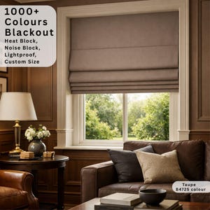 Può includere: Una tenda a pacchetto color tortora installata su una finestra, con il testo 1000+ Colours Blackout, Heat Block, Noise Block, Lightproof, Custom Size. La tenda è di un colore neutro a tinta unita, posizionata sopra un divano con cuscini.