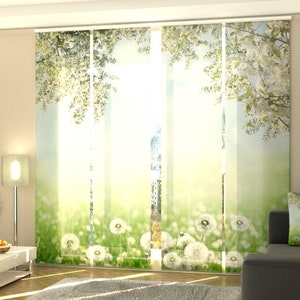 Puede incluir: Cortinas blancas y transparentes con un estampado floral de flores blancas y hojas verdes. Las cortinas tienen un fondo azul claro con una imagen borrosa de un campo de dientes de león.