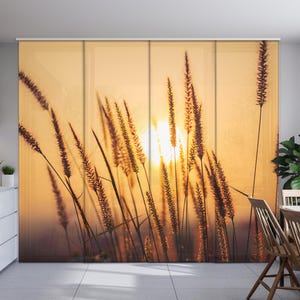 May include: A sunset scene with tall grass silhouetted against a bright orange sky. The grass is a dark brown colour and the sky is a vibrant orange with a hint of yellow.