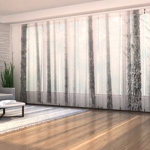 May include: White sheer curtains with a black and white tree print. The curtains are hung in a living room with a gray sofa, a coffee table, and a potted plant.