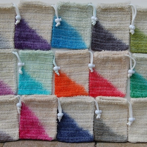 May include: A collection of 16 small, square, crocheted bags with a diagonal color gradient. The bags are made of natural fiber and have a white drawstring closure. The colors include purple, blue, gray, green, pink, orange, turquoise, and red.