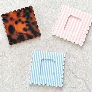 Puede incluir: Tres marcos cuadrados decorativos con bordes festoneados. Uno tiene un patr&oacute;n de carey, los otros dos presentan rayas verticales en rosa y azul. Cada marco tiene una abertura rectangular en el centro.