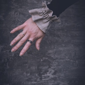 May include: A set of three ceramic mugs with a speckled, matte finish. The mugs are in cream, light grey, and dark grey. Each mug has a simple, minimalist design, ideal for coffee or tea.