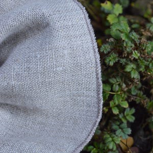 May include: A white ceramic mug with a black handle and the text "But First, Coffee" in a bold, black font. The mug is set against a blurred background. The mug appears to be approximately 10 cm tall.