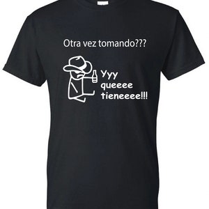 May include: Black t-shirt with a white stick figure wearing a cowboy hat and holding a bottle. The text "Otra vez tomando??? Yyy queeee tieneeeee!!!" is printed on the shirt.