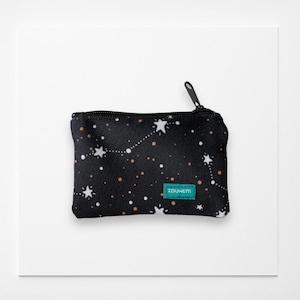 Pode incluir: Bolsa preta com zíper e um padrão de constelação de estrelas brancas e pontos dourados. A bolsa tem uma pequena etiqueta turquesa que diz "ZDUNETTI". O zíper é preto.