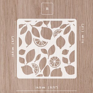 May include: A square stencil with a lemon and leaf design. The stencil is 5.71 inches wide, 5.3 inches tall, and 1.2 inches thick. The stencil has a repeating pattern of lemons, lemon slices, and leaves. The letter "B" is in the upper left corner.