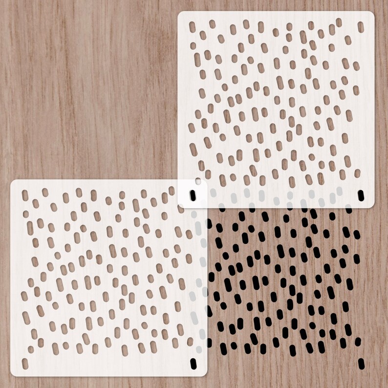 May include: Two white stencils with a black and white pattern of small ovals. The stencils are on a woodgrain background.