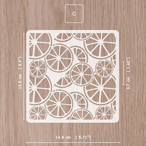 May include: A white square stencil featuring a pattern of orange slices. The stencil measures 5.71 inches wide and 5.3 inches tall. The stencil has a small square with the letter "C" in the upper left corner. The stencil is 1.45 inches wide.