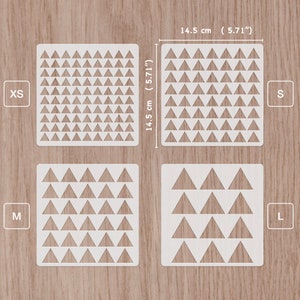 Peut inclure: Quatre pochoirs en plastique blanc avec un motif de triangles répétés. Les pochoirs sont étiquetés XS, S, M et L. Les pochoirs mesurent 14,5 cm sur 14,5 cm.