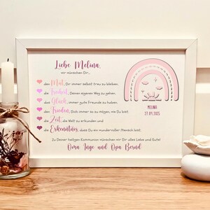May include: A white framed print featuring a pink rainbow graphic, the name Melina, and the date 27.04.2025. The text includes German wishes for courage, freedom, happiness, peace, time, and knowledge, signed by Oma Inge and Opa Bernd.