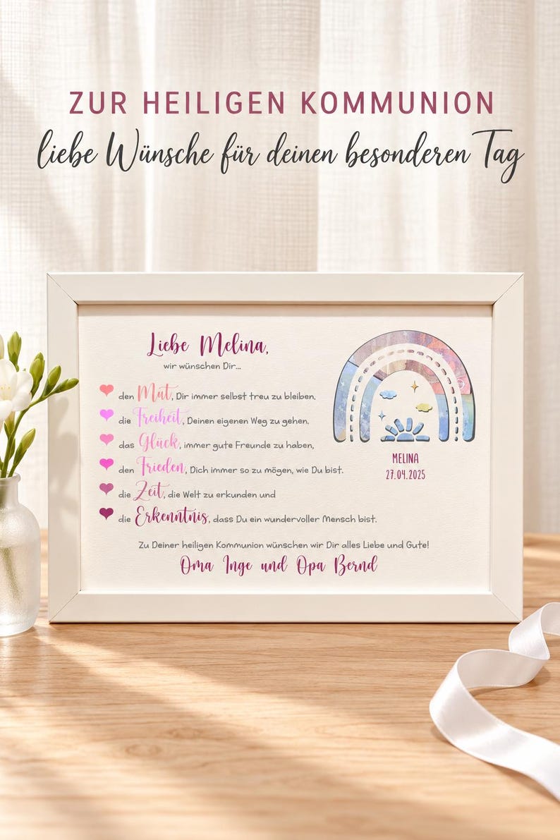May include: A white rectangular frame containing a personalized print for a First Communion. The print features the text 'Liebe Melina', a list of wishes with heart icons, a watercolor-style rainbow illustration, and the name 'MELINA' with the date '27.04.2025'.