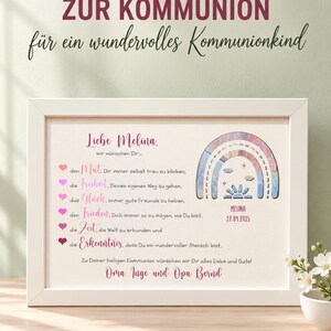 May include: A white rectangular frame containing a personalized print for a communion. The text reads 'HERZENSW&Uuml;NSCHE ZUR KOMMUNION', 'Liebe Melina', and includes a list of wishes with pink heart icons. A colorful rainbow graphic features the name 'MELINA' and the date '27.04.2025'.