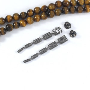 May include: A pair of long, silver dangle earrings with multiple rectangular-shaped stones. The stones are set in a pave setting and have a sparkly finish. The earrings are hanging from a silver post with a butterfly back.