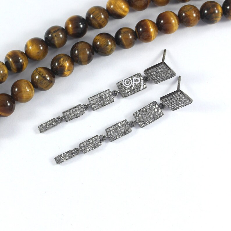 May include: A pair of long silver dangle earrings with multiple rectangular-shaped charms encrusted with small clear diamonds.