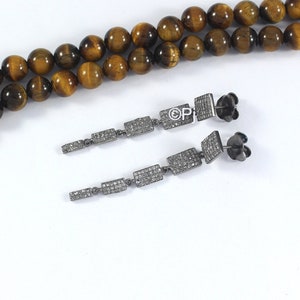 May include: A pair of long silver dangle earrings with a row of small square-shaped stones. The stones are set in a silver frame and are connected by a thin silver chain.