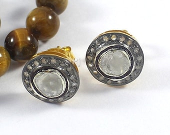 May include: A pair of gold earrings with a round, white gemstone surrounded by a halo of small, black diamonds.