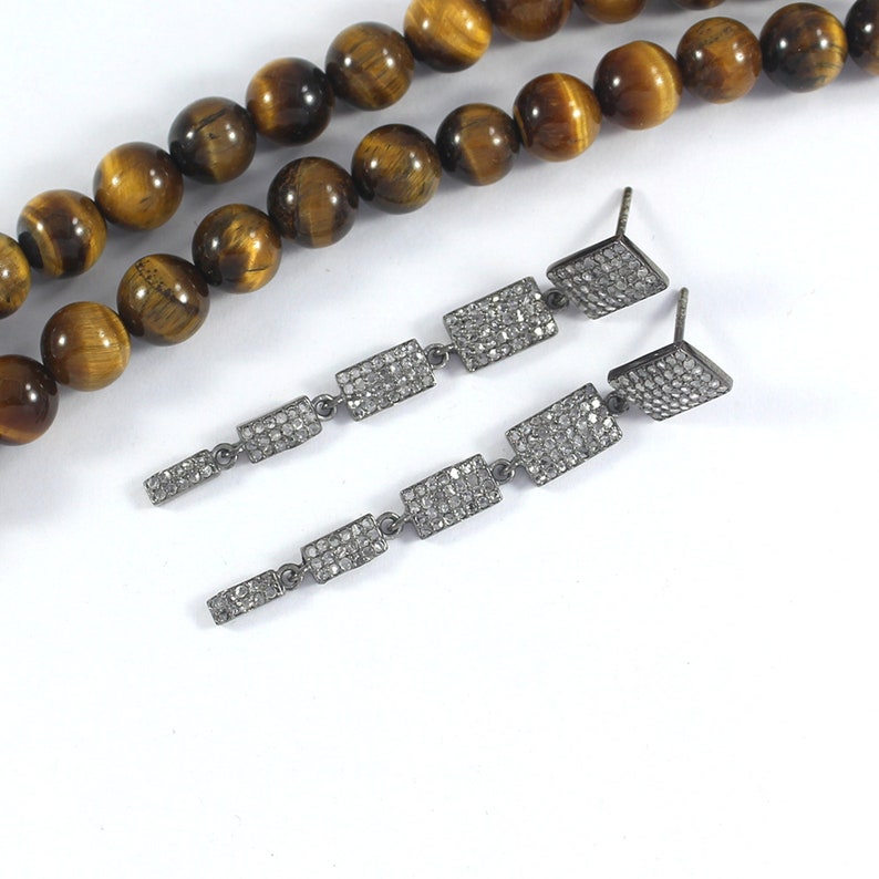 May include: A pair of long silver dangle earrings with multiple rectangular-shaped charms encrusted with small clear stones.