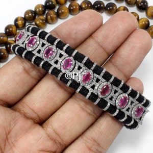 Può includere: Un braccialetto intrecciato nero con una catena d'argento e pietre ovali rosa. Le pietre preziose sono incastonate in una cornice d'argento con diamanti più piccoli.