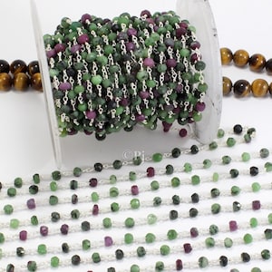 May include: A spool of green and purple gemstone beads strung on a silver chain. The beads are approximately 4 mm in diameter and are ideal for making jewellery.