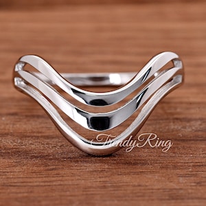 May include: Silver ring with a triple wave design. The ring is open and adjustable.