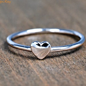 May include: A simple silver ring with a small heart-shaped design.