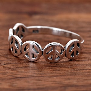 May include: A silver peace sign ring with multiple peace signs around the band.