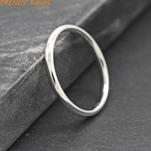 May include: A simple silver band ring. The ring is thin and has a smooth, polished finish.
