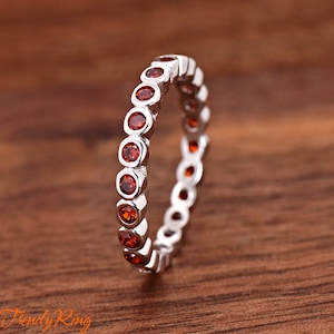 May include: A silver band ring with a row of small, round, orange gemstones.