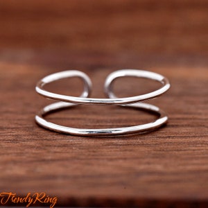 May include: A silver double band ring with a simple design. The ring is made of two bands of metal that are joined together.