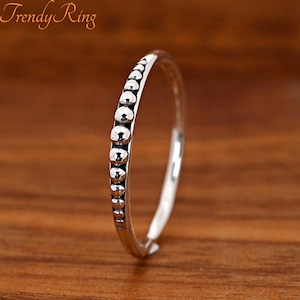 May include: A silver-toned ring featuring a series of small, raised, rounded beads along the outer band. The metal has a polished finish with darkened recessed areas between the beads. The text "Trendy Ring" is visible in the upper left corner.