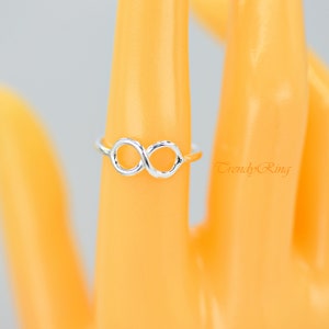 May include: A silver infinity symbol ring. The ring is on a mannequin hand.