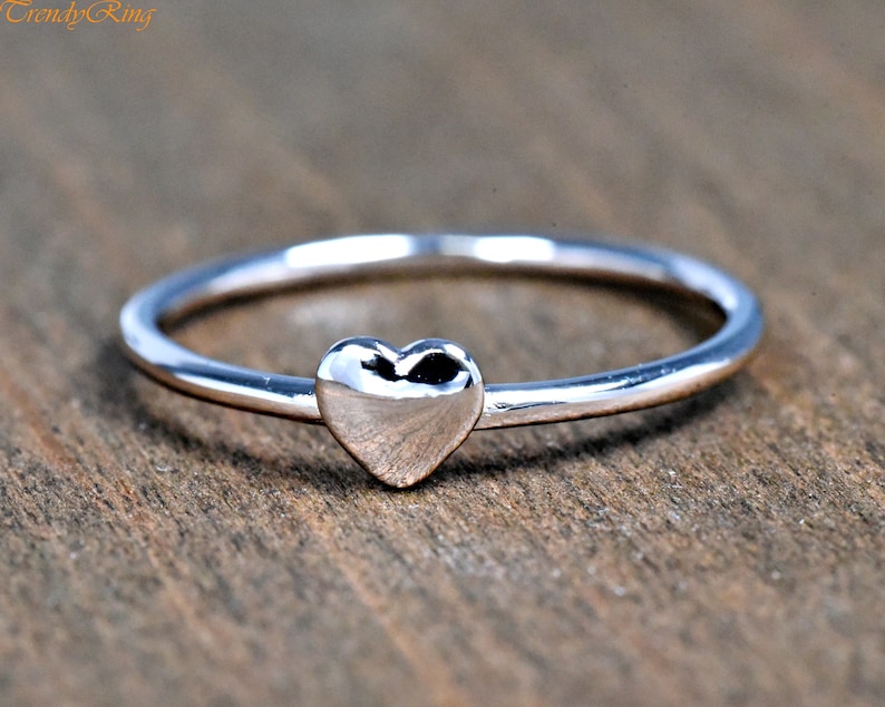May include: A simple silver ring with a small heart-shaped design.