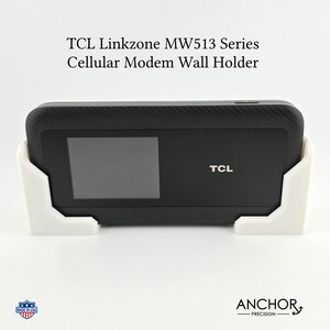 May include: A white wall mount for a TCL Linkzone MW513 series cellular modem. The modem is black with a screen and the TCL logo.