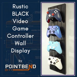 May include: A vertical black wooden wall mount holding four video game controllers. The controllers are dark blue with red accents, metallic blue, light blue, and white. The text on the left reads: Rustic BLACK Video Game Controller Wall Display by POINTBEND.