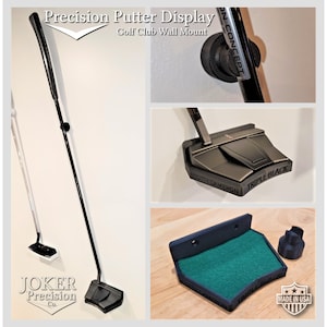 May include: A black golf club wall mount with a green felt pad and a black plastic cap. The mount is labelled "Triple Black" and "Scotty Cameron". The text "Made in USA" is visible in the bottom right corner.