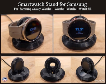 May include: A black 3D printed stand for a Samsung Galaxy smartwatch. The stand has a circular base and a raised platform to hold the watch. The watch is shown on the stand with the time 13:51 displayed on the screen.