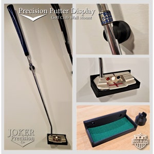 May include: A black wall mount for displaying a golf putter. The mount is made of plastic and has a green felt lining. The mount is labeled "Made in USA".