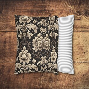 May include: Two decorative pillows, one with a black background and a beige floral pattern, and the other with a white background and gray stripes.