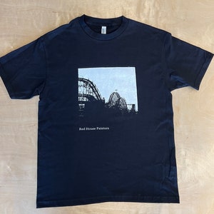 May include: Black t-shirt featuring a white graphic of a roller coaster silhouette. The text "Red House Painters" is printed below the graphic.