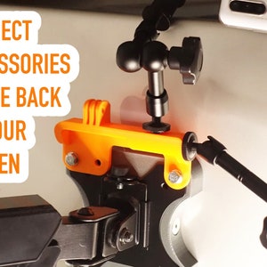 May include: A black and orange 3D printed phone mount with a black arm extending out. The text "CONNECT ACCESSORIES TO THE BACK OF YOUR SCREEN" is visible in the image.