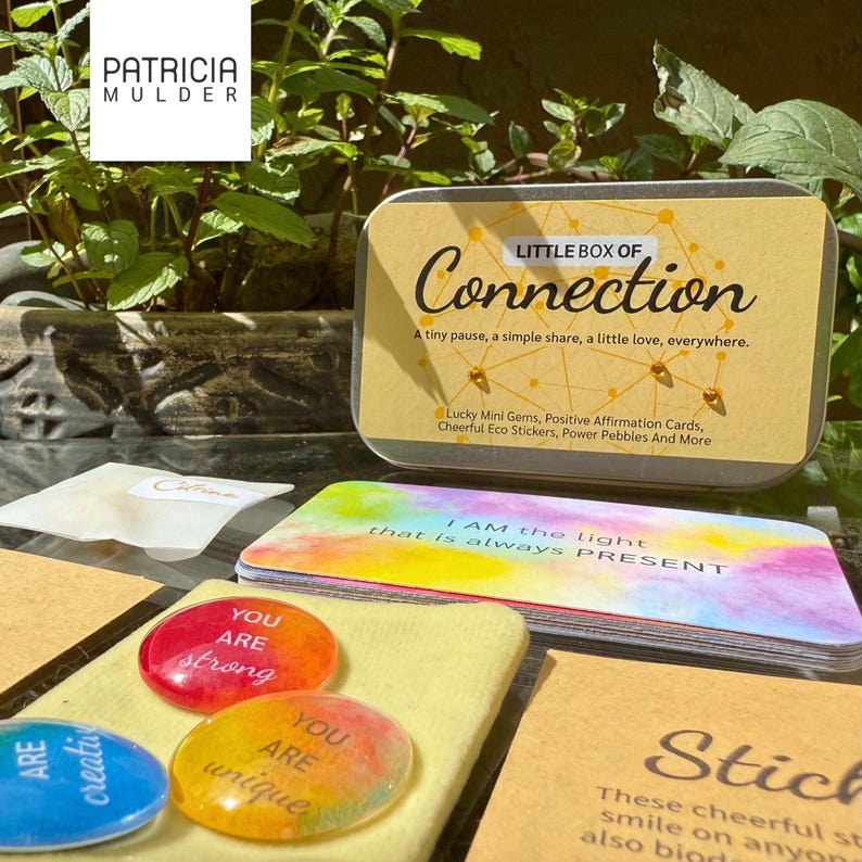 Little box of connection made to inspire and bring people together. Includes discovery papers that ask meaningful prompts and power glass pebbles with you are kind, you are strong and other versions. Also 9 affirmation cards, and a small glassine envelope with 6 little gemstones. There’s also a paper pouch with 3 eco friendly stickers in this box. You can pick a blue, yellow or green front and citrine, amethyst or rose quartz gems. Share with friends, lift spirits and gift the gift of connection
