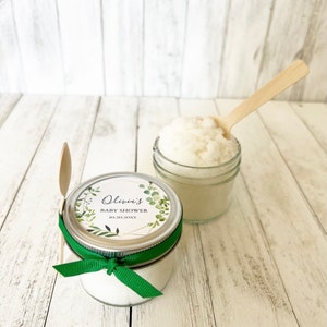 May include: A small glass jar filled with white bath salts, tied with a green ribbon and a personalised label that reads "Olivia's Baby Shower 10.20.20XX".