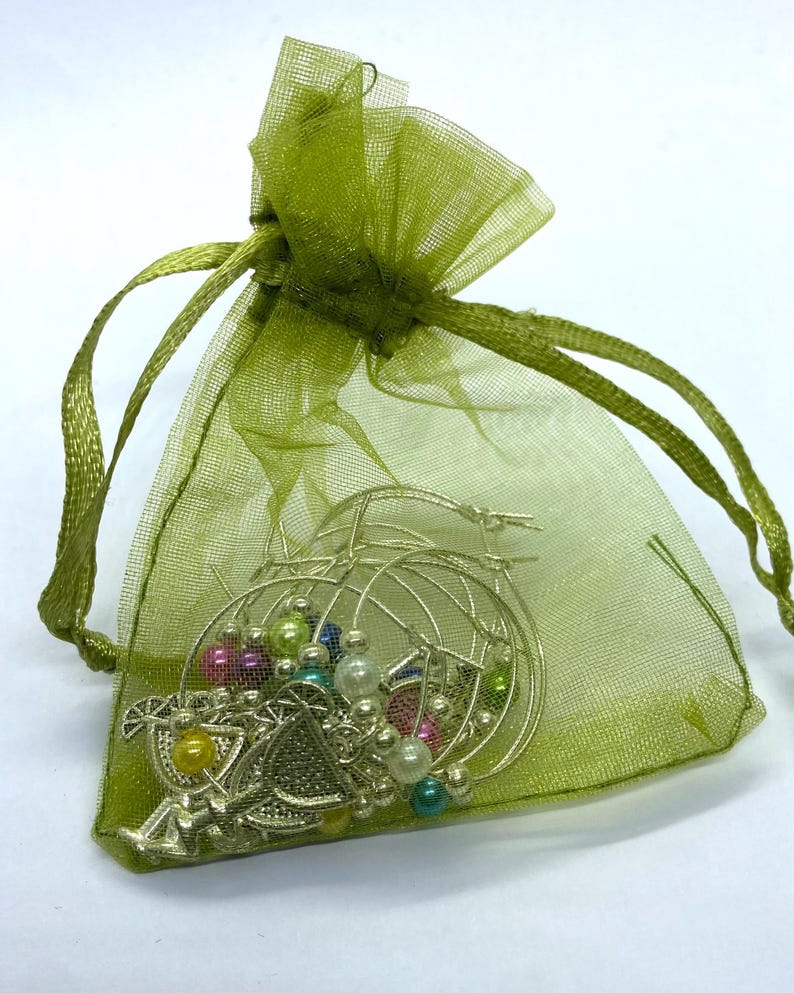 May include: A sheer lime green organza drawstring pouch containing several silver-toned hoop earrings. The earrings are decorated with small, round, multi-colored beads in shades of yellow, pink, blue, and white, along with silver metal charms.