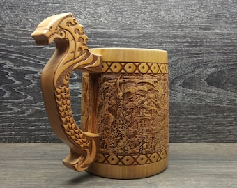 Può includere: Un boccale di birra in legno con un manico a forma di drago intagliato e incisioni in rilievo dettagliate. Il boccale è in legno chiaro e presenta opere d'arte complesse.