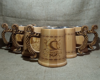 May include: A collection of wooden beer mugs with ornate handles and engraved designs. Each mug features a decorative border and a personalized engraving with the name "Stinson" and the letter "S". The mugs have a light wood finish and a silver interior.