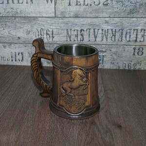 May include: A wooden beer stein with a stainless steel liner. The stein features a carved image of a horse with the words "Prancing Pony" underneath.