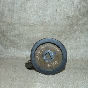 May include: A wooden bottle opener with a black metal ring around the edge. The bottle opener has the inscription "The One Ring" in Elvish script.